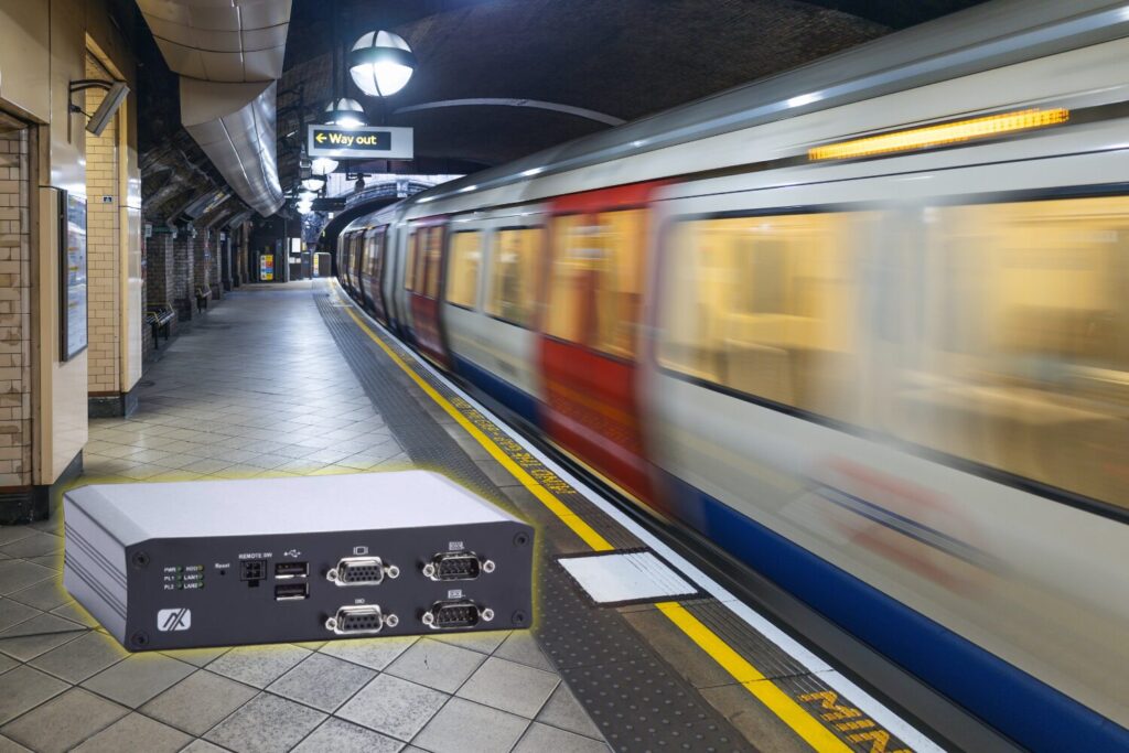 A blurred train speeding past a platform and a computer in the foreground